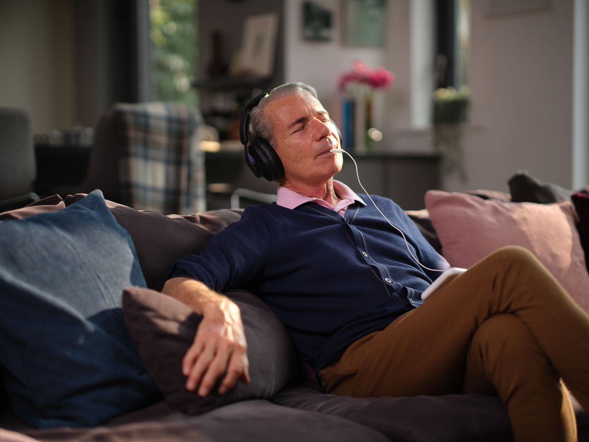A person relaxing at home while using the Lenire tinnitus treatment device