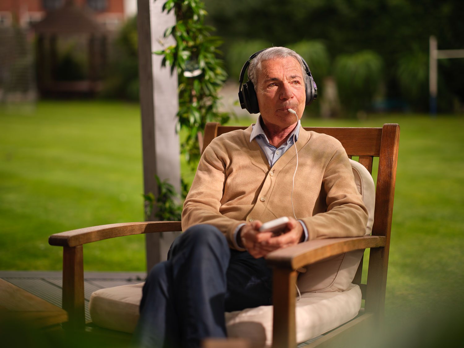 A man relaxing in a garden chair wearing the Lenire headphones