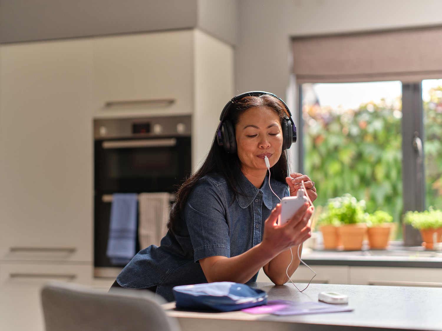 A woman using Lenire at a kitchen table while she reads and takes notes