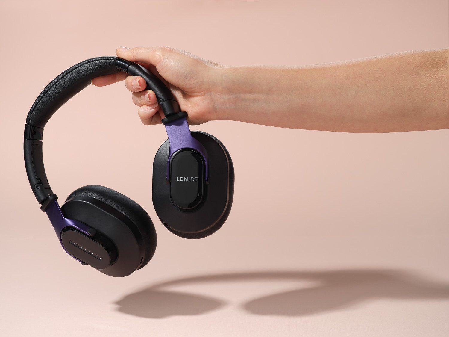A hand holding the Lenire Bluetooth headphones