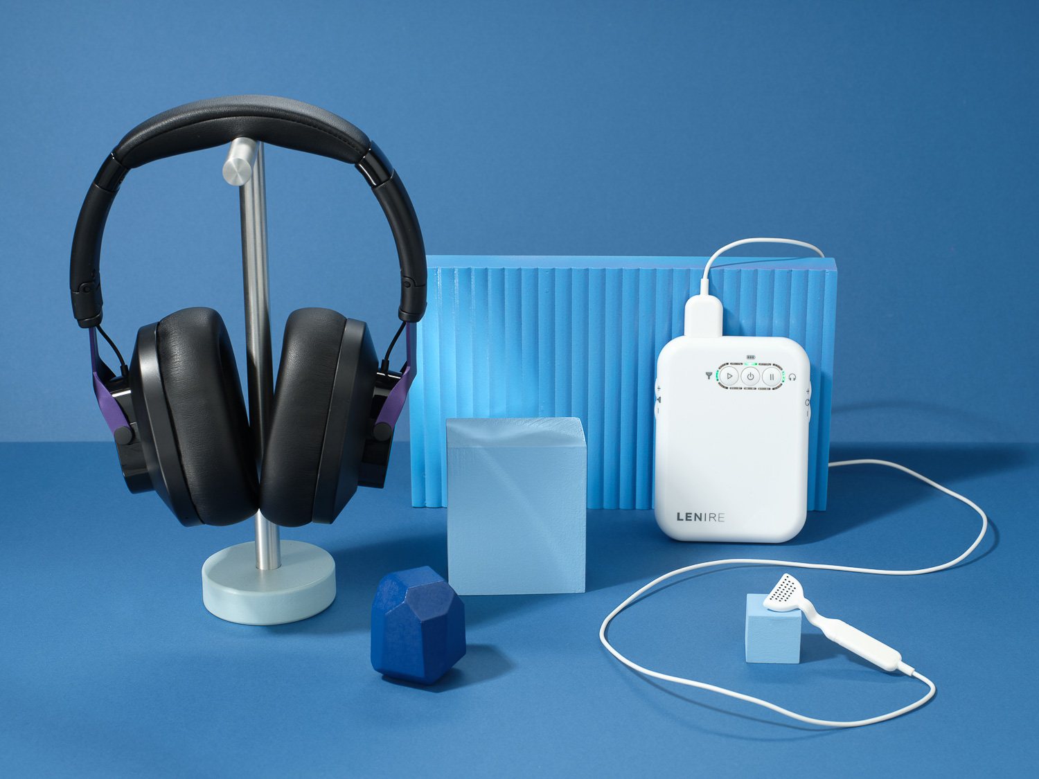 The Lenire tinnitus treatment device: Bluetooth headphones on a stand, the handheld controller and the Tonguetip