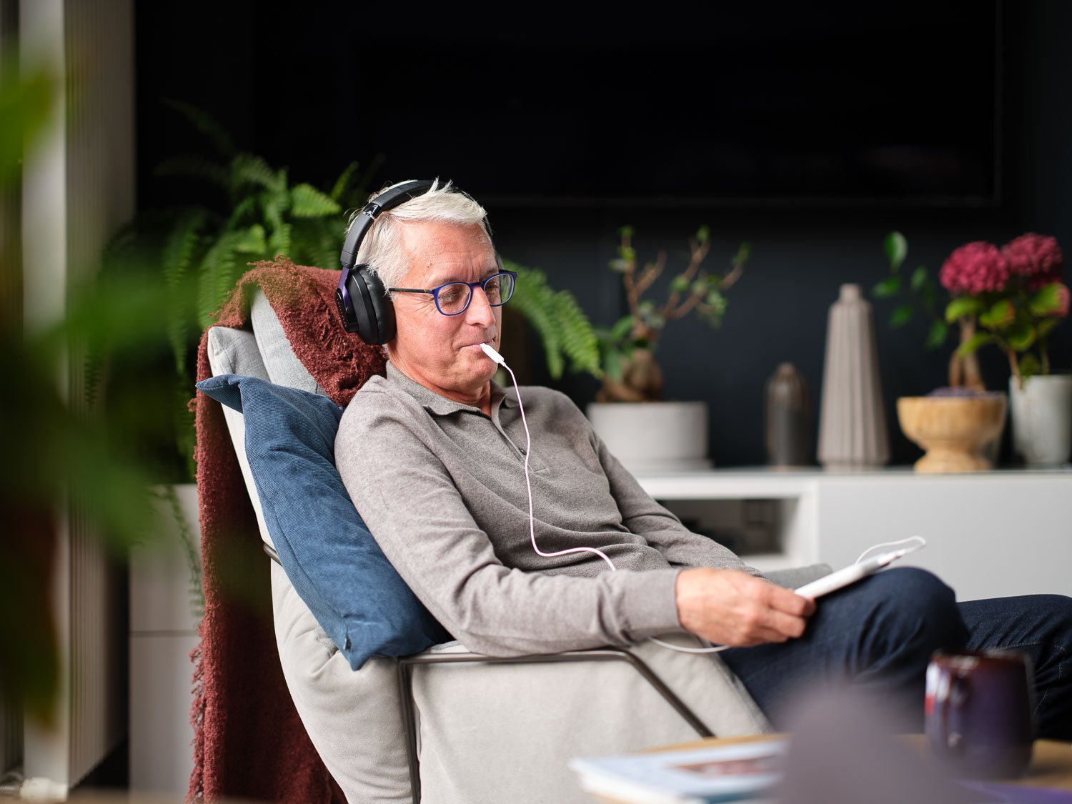 A man relaxing in a recliner at home wearing the Lenire headphones