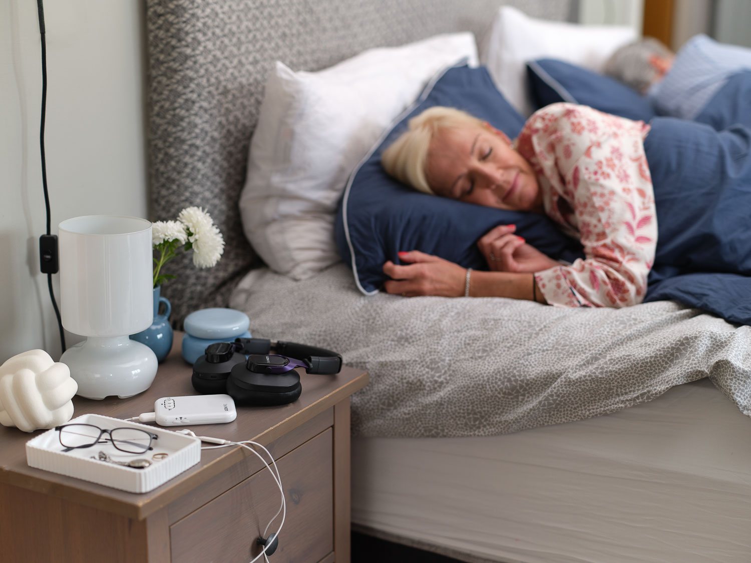 A person sleeping peacefully with the Lenire device on the bedside table